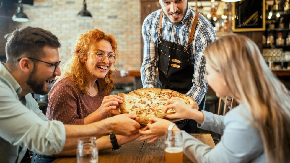 Group of people eating pizza in a restaurant 